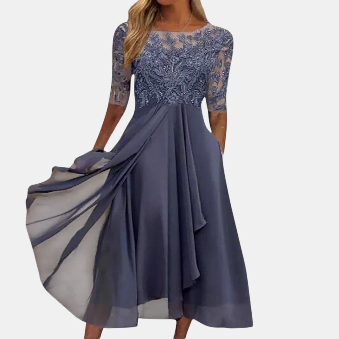 Elegant dark blue dress with lace bodice and flowing skirt, studio background.