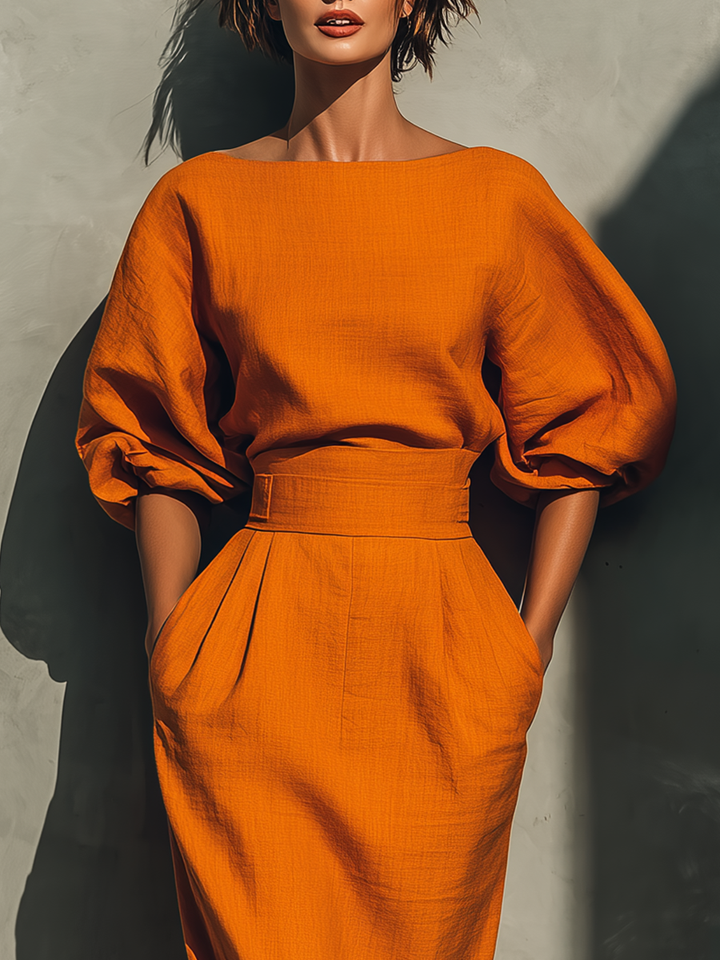 Close-up of orange skirt set with structured top and puff sleeves in a studio setting.