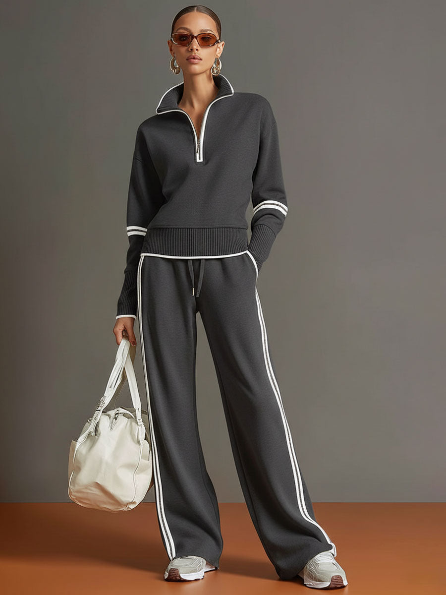 Effortless matching lounge set in dark gray with contrast stripes, styled with white sneakers and a bag in a studio setting.