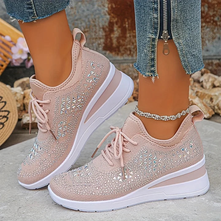 Light pink orthopedic sneakers with detailed sparkle worn outdoors, contrasted against denim and natural textures.