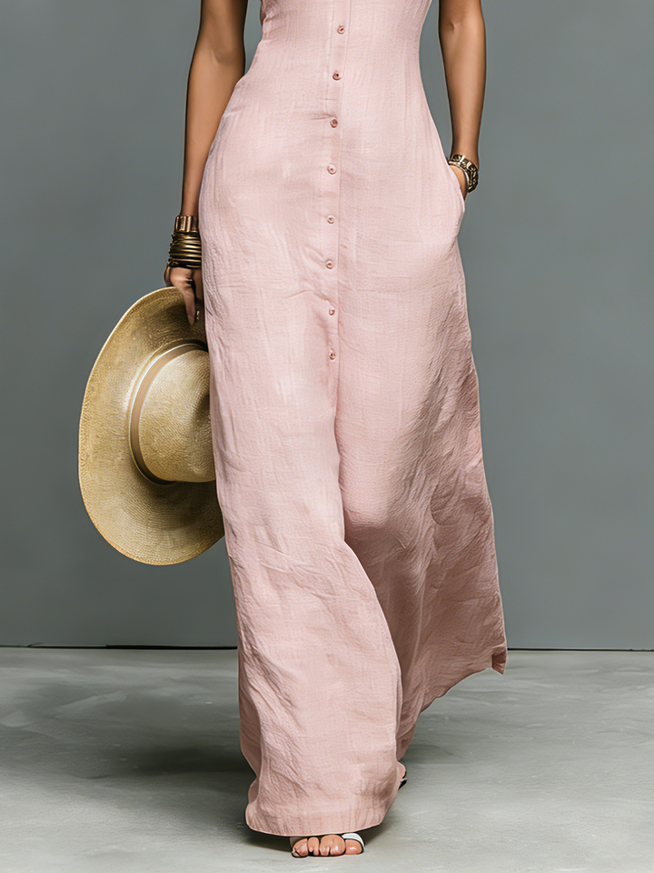 Lower part of pink maxi dress with button details held by model, studio background.