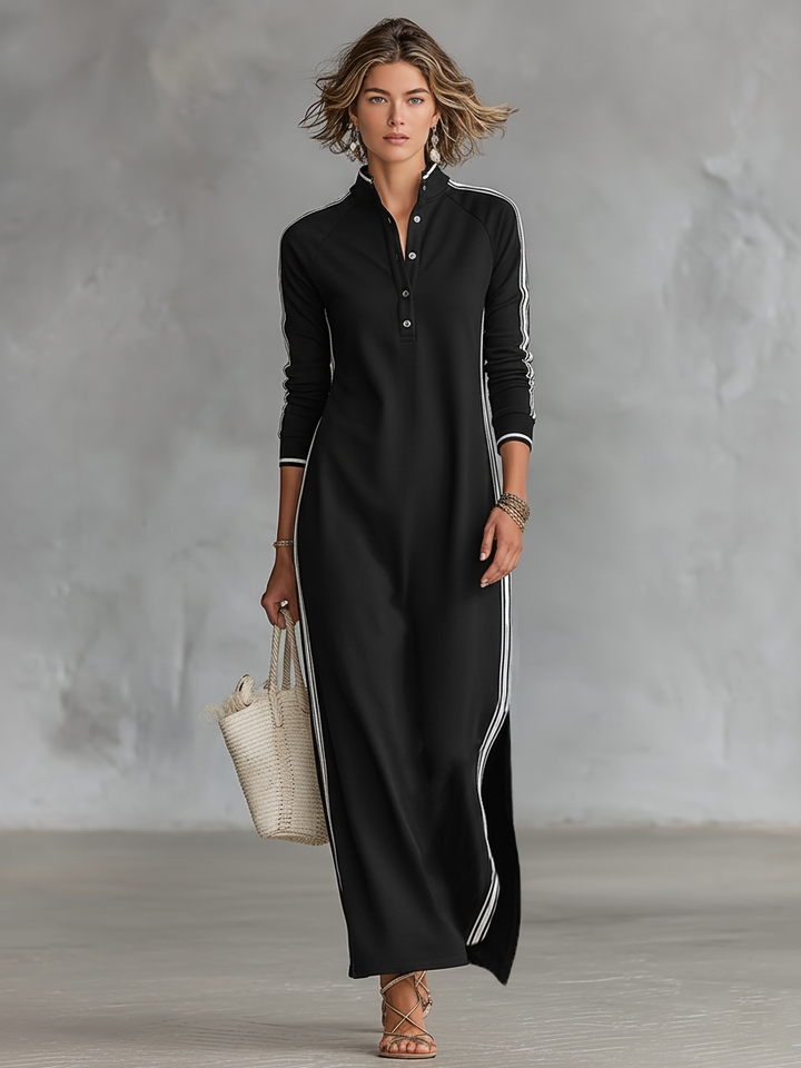 Black maxi dress with vertical stripes, worn by a person holding a woven tote. Neutral indoor background.