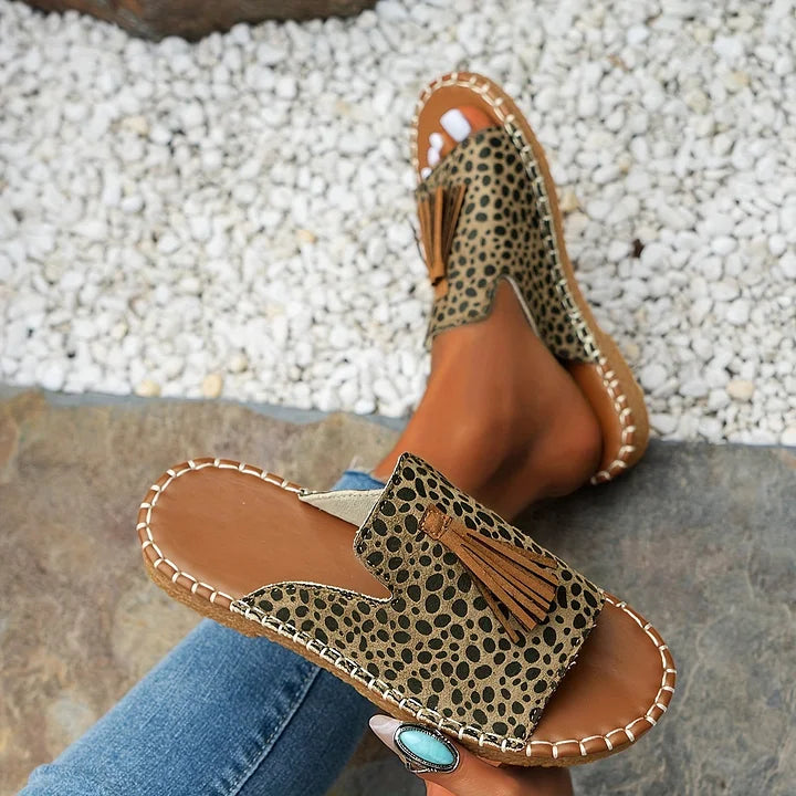 Person relaxing outdoors wearing polka dot orthopedic sandals with tassels on stone path.