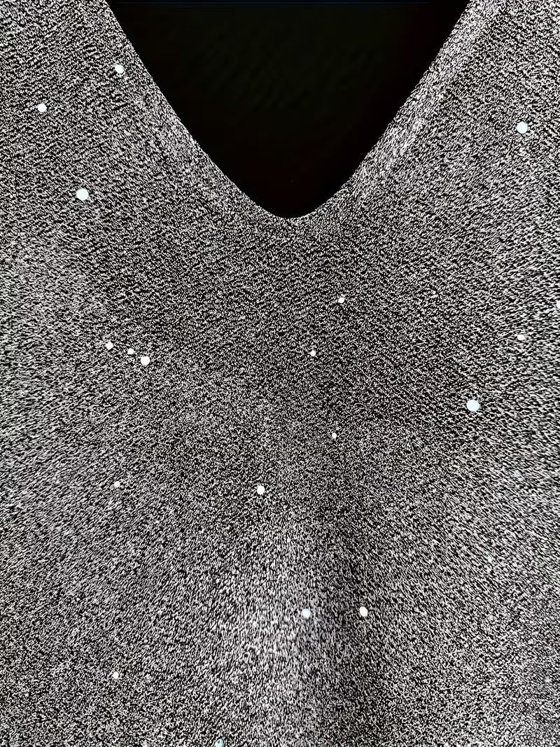 Close-up of a grey dress fabric with shimmering detail and V-neckline, highlighting texture and sparkle.