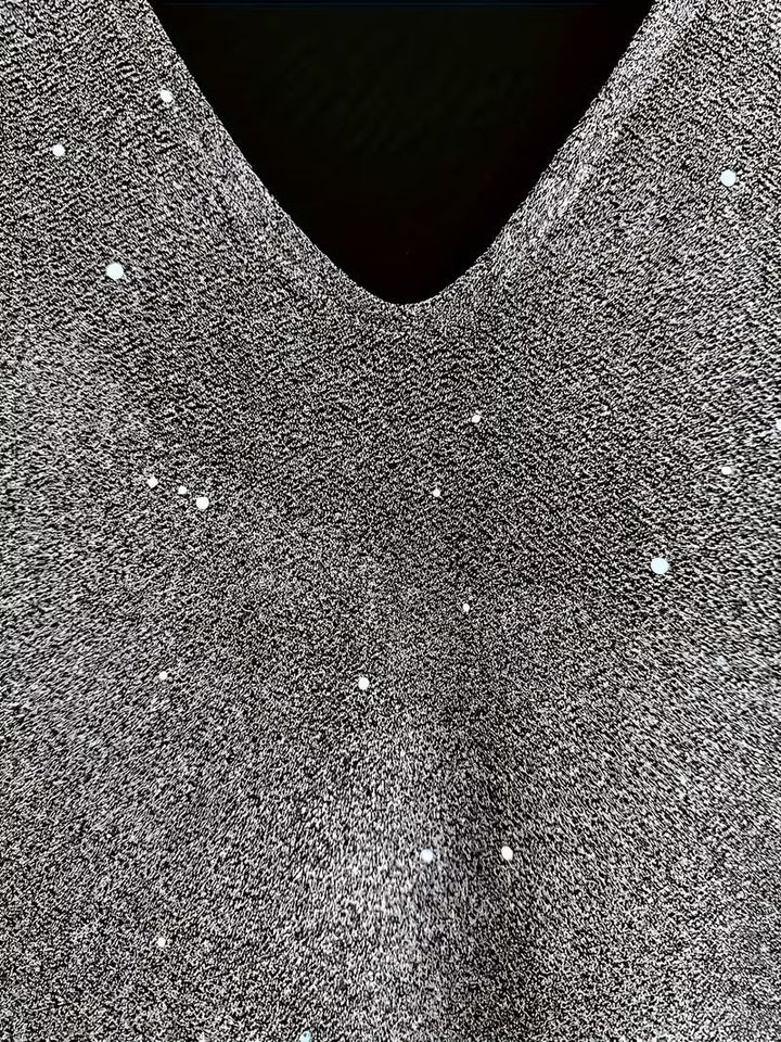 Close-up of a grey dress fabric with shimmering detail and V-neckline, highlighting texture and sparkle.