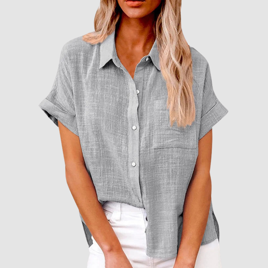 Gray casual blouse with short sleeves and front buttons, worn in white jeans. Studio background.