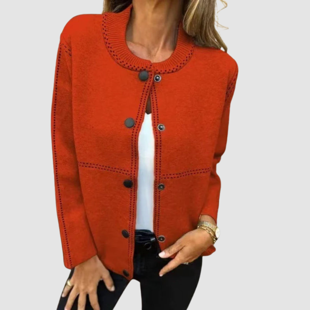 Orange jacket with round collar, button closure, worn over white top and black pants in a studio setting.