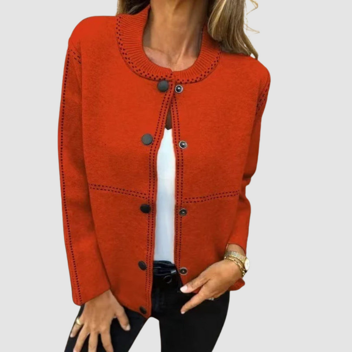Orange jacket with round collar, button closure, worn over white top and black pants in a studio setting.