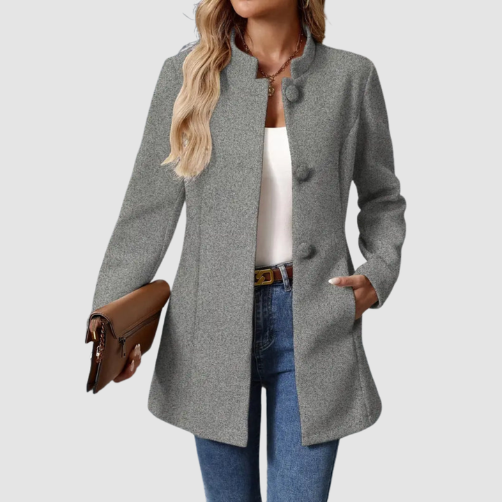 Gray jacket, large buttons, worn over white top and jeans, holding clutch, against plain background.