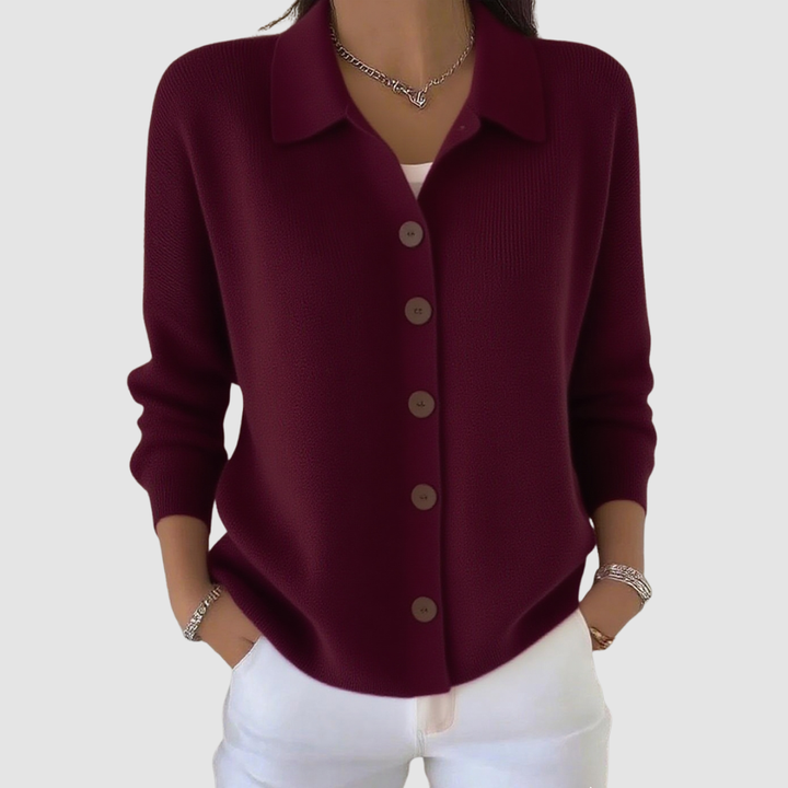 Burgundy button-up knit cardigan with brown buttons, worn with white pants in a studio setting.