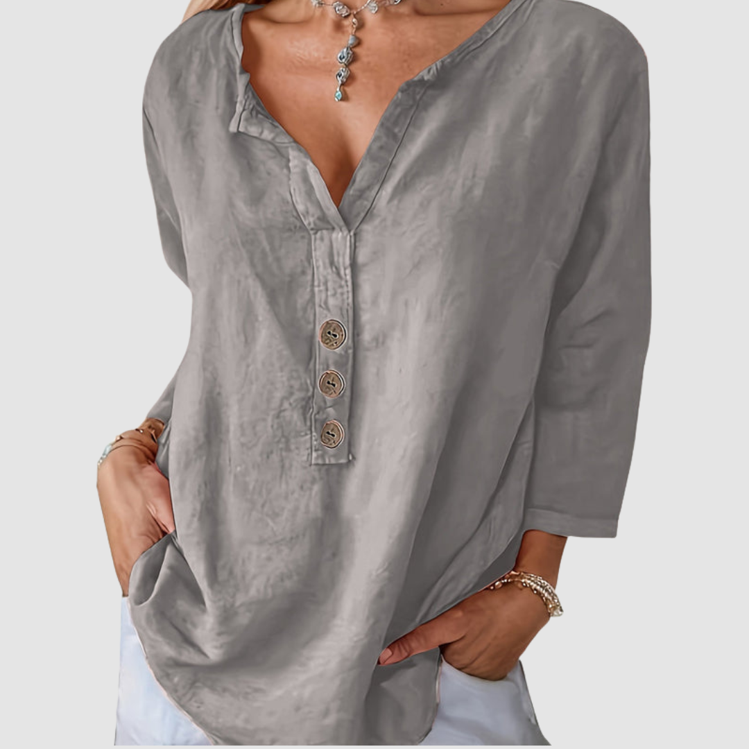 Casual grey blouse with button detail, worn by a model with a necklace, against a plain background.