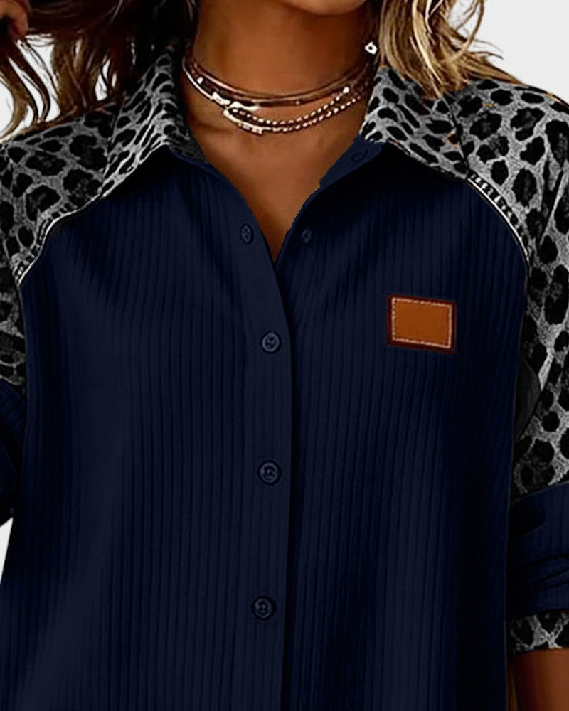 Close-up of leopard print button-down shirt top. Navy shirt with patterned collar and black buttons in a studio.