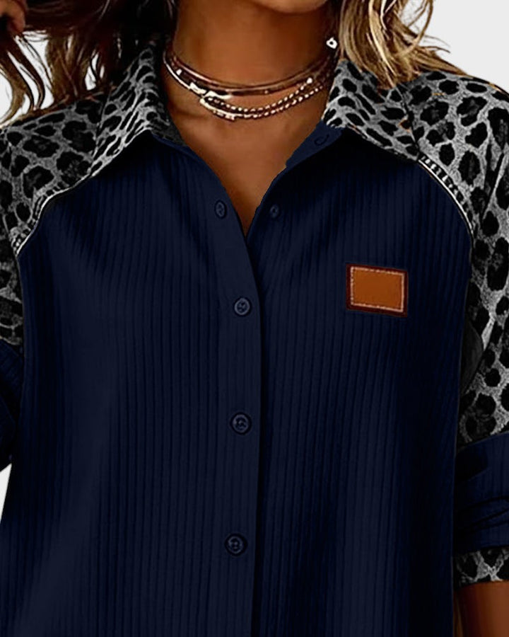 Close-up of leopard print button-down shirt top. Navy shirt with patterned collar and black buttons in a studio.
