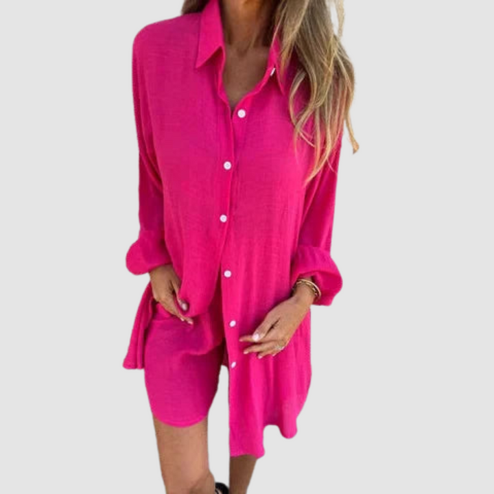 Model wearing a pink two-piece set with button-up shirt and shorts; neutral studio background.