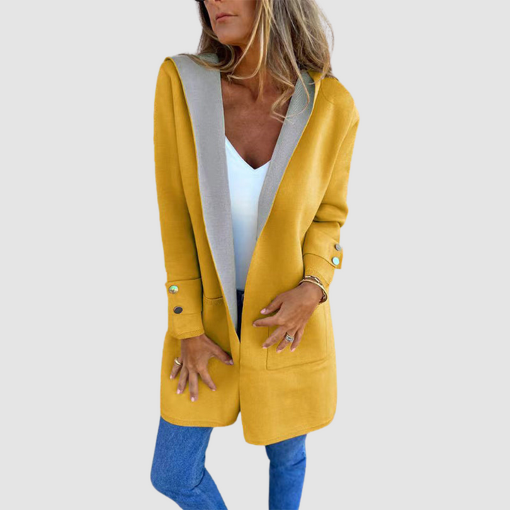 Mustard and gray colorblock hooded jacket worn over white top and jeans in a studio setting.