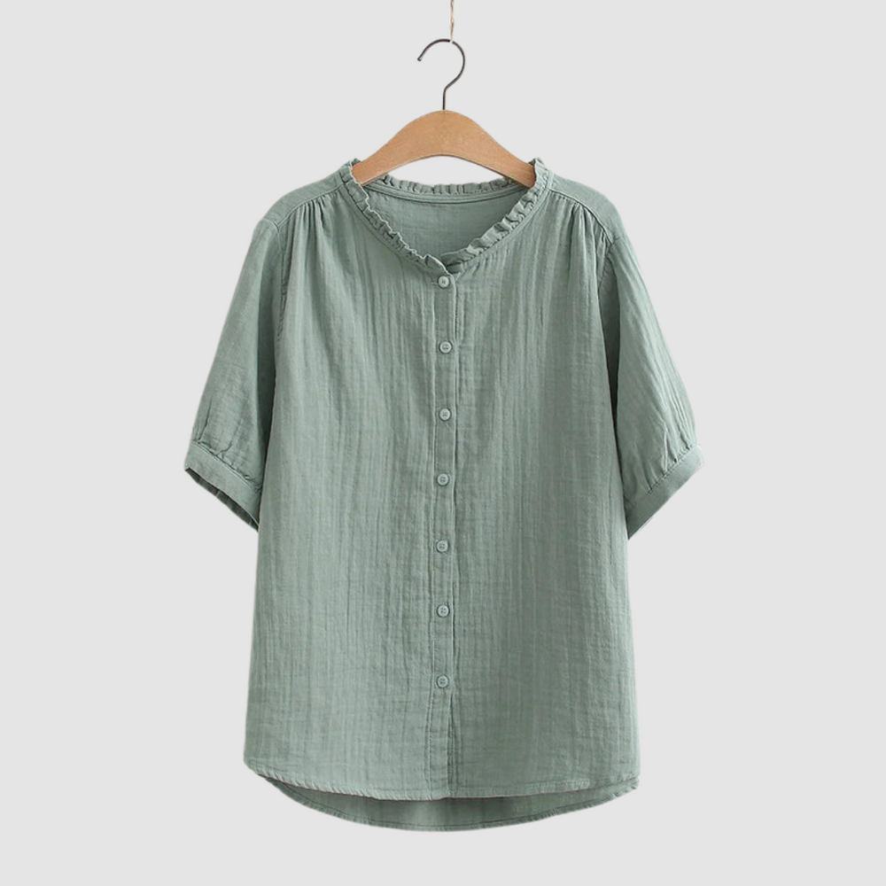 Sage green button-up shirt with ruffled collar on wooden hanger, studio background.