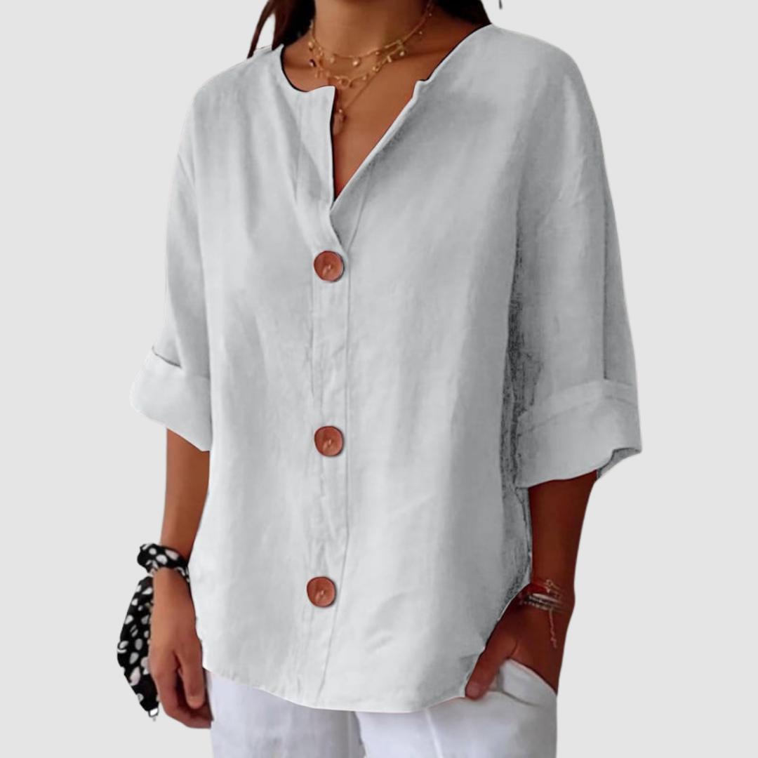 Light gray casual blouse with prominent buttons, turned-up sleeves, on a neutral background.