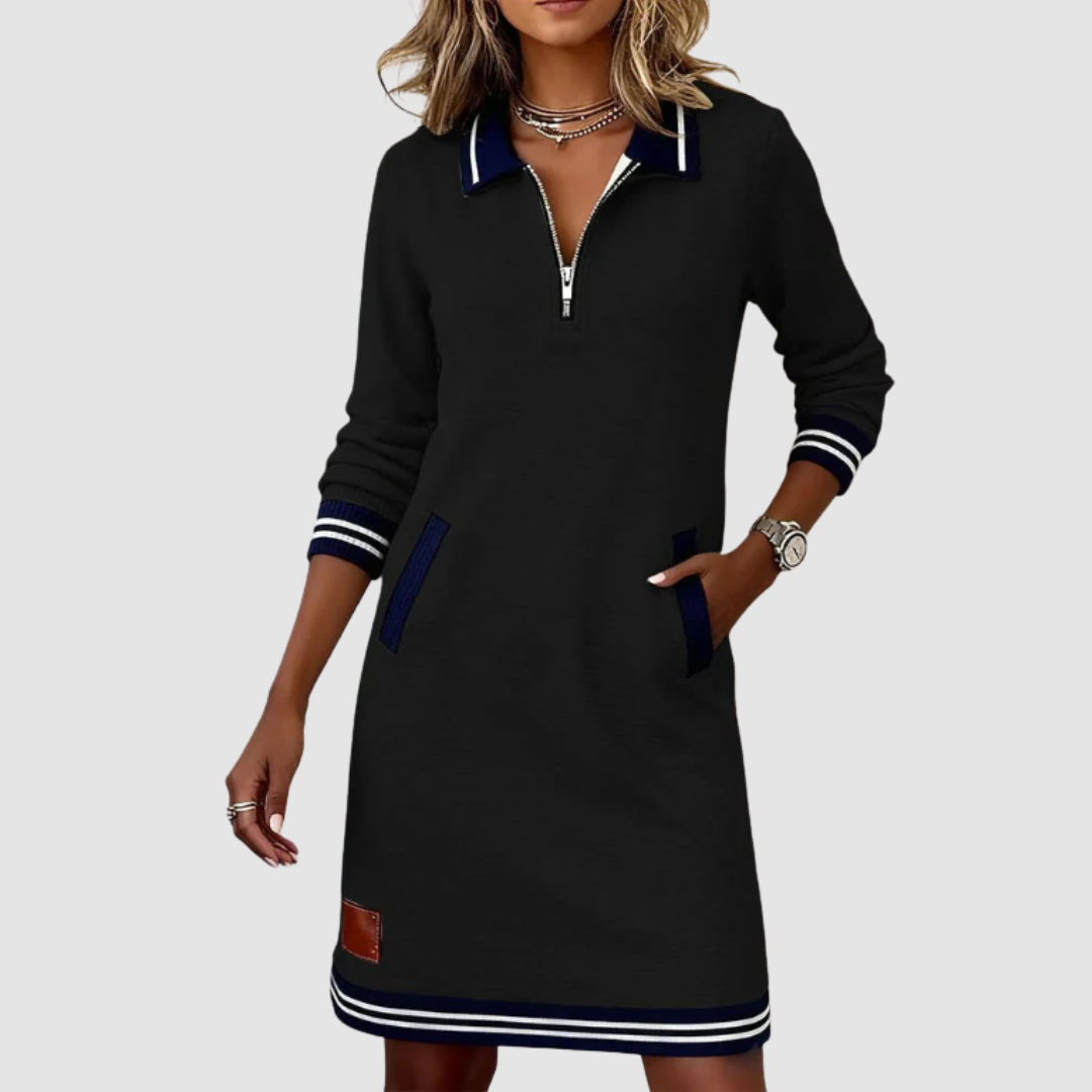 Sleek black zip-neck dress with navy accents and pockets, modeled by a woman wearing accessories in a studio setting.