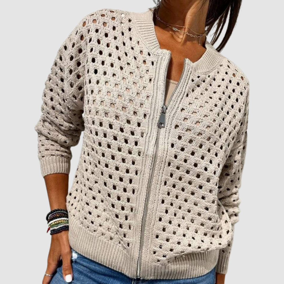 Light beige knitted cardigan with a zip front, perforated design, and long sleeves in a studio setting.