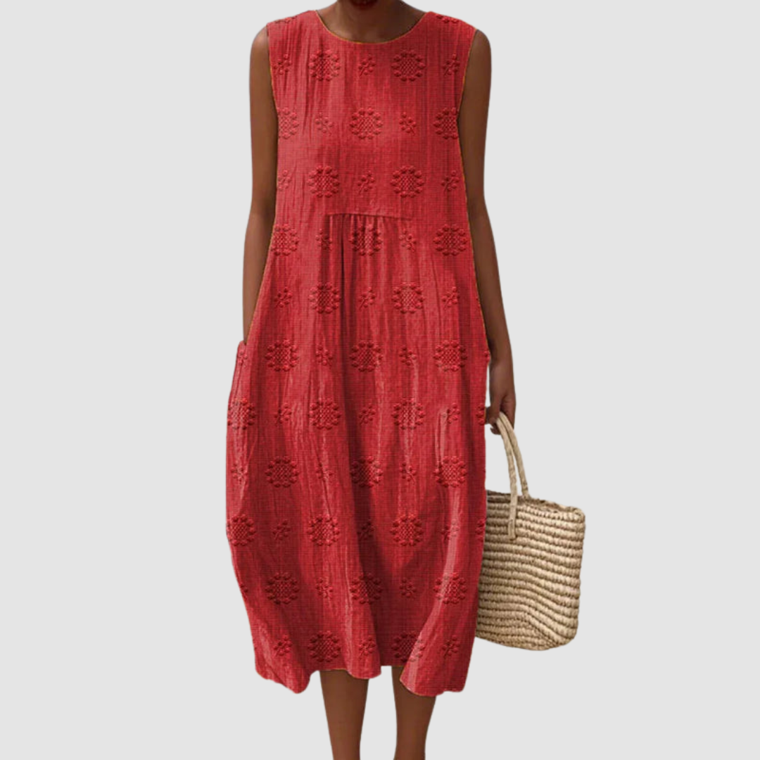 Red sleeveless summer dress with floral patterns, model holding a woven basket, white background.