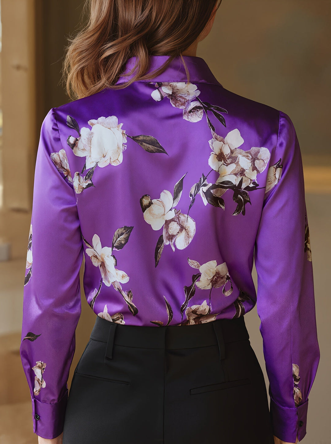 Back view of purple satin blouse with floral design, model posing indoors, neutral setting.