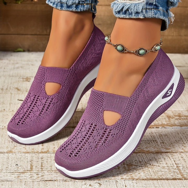 Purple non-slip orthopedic shoes worn with anklet, distressed jeans on wooden floor.