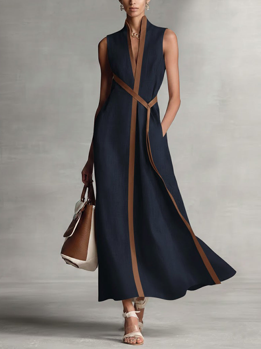 Chic sleeveless black maxi dress with brown trim, accessory with a handbag and sandals in a studio setting.