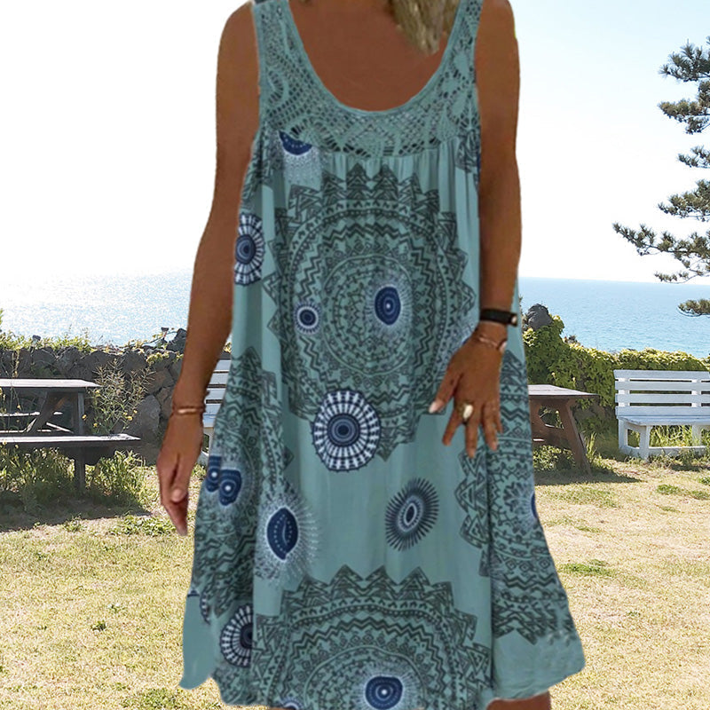 Woman in light blue printed dress standing outdoors with ocean in background.