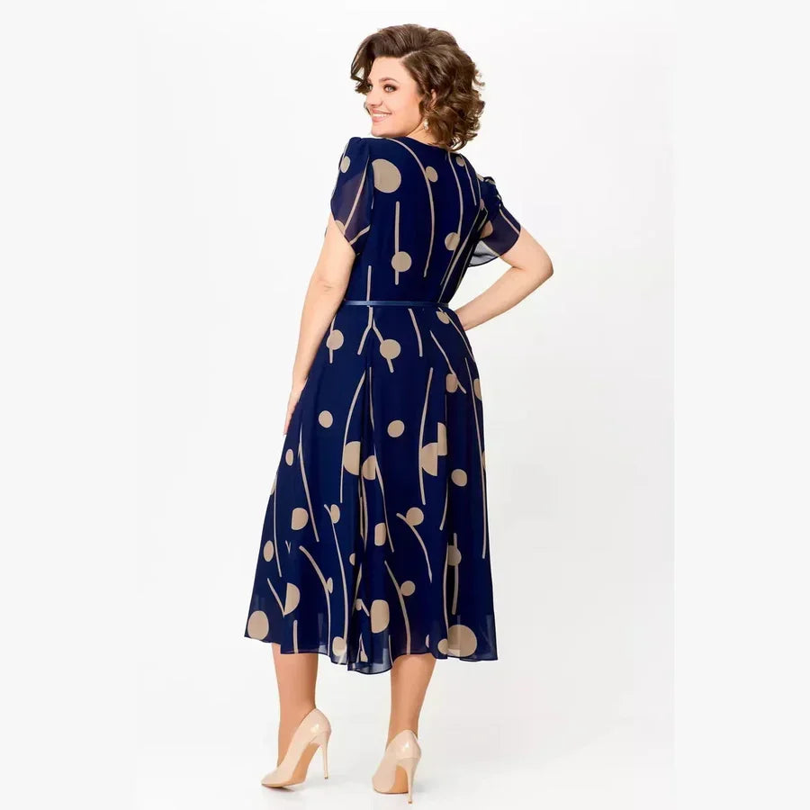 Back view of navy polka dot chiffon midi dress, highlighting the flowy fabric and short sleeves in a studio.