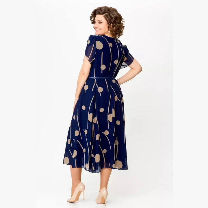 Back view of navy polka dot chiffon midi dress, highlighting the flowy fabric and short sleeves in a studio.