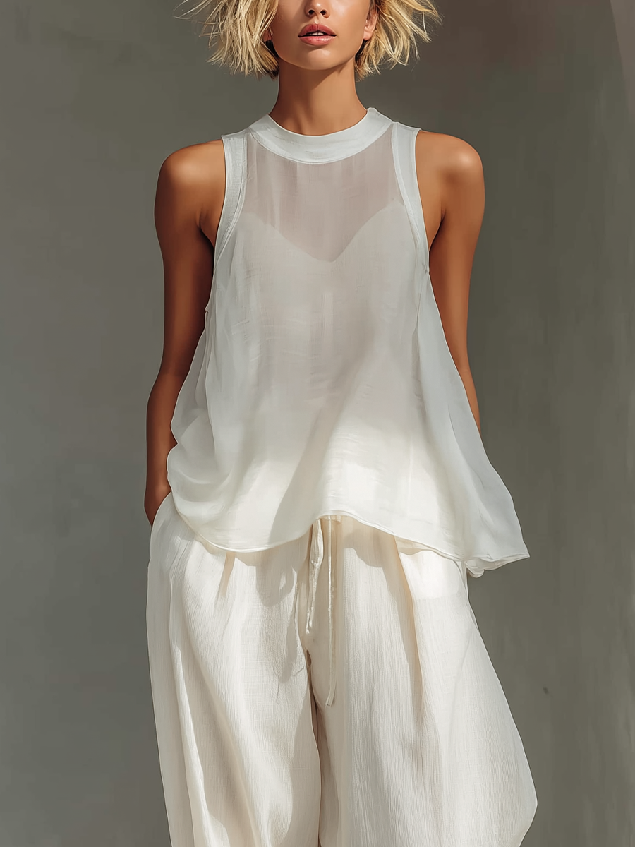 Close-up of a white sheer top and drawstring pants set, worn by model against neutral background.