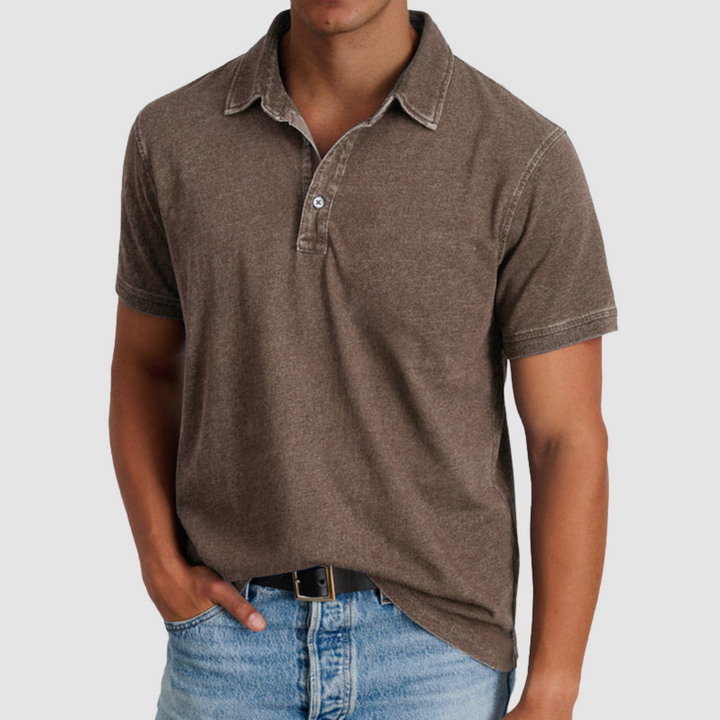 Model wearing a brown classic collared polo with short sleeves, buttoned placket, light denim jeans in a studio setting.
