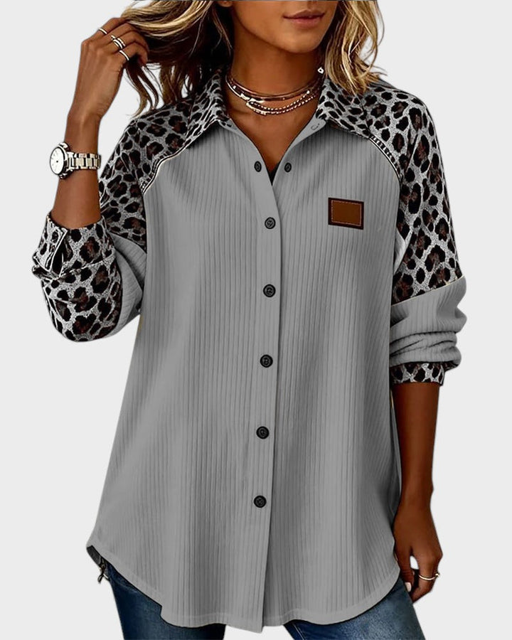 Leopard print button-down shirt in gray with black buttons. Patterned collar and sleeves. Worn by model in a studio.