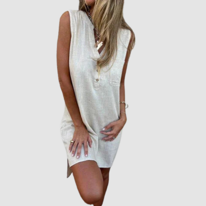 Woman in a light-colored sleeveless dress with button details, posing with one knee bent. Studio background.