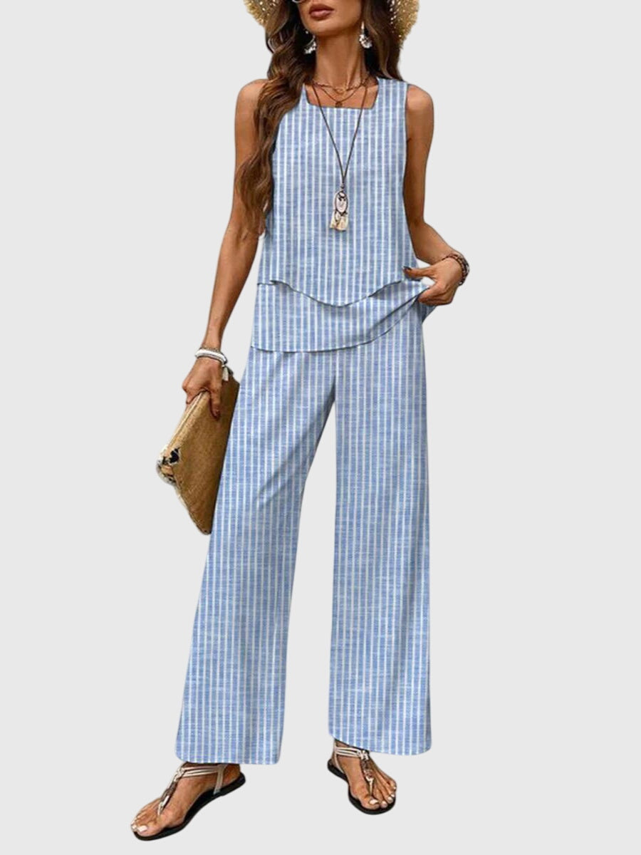 Model in striped sleeveless top with layered hem and striped wide-leg pants. Neutral backdrop.