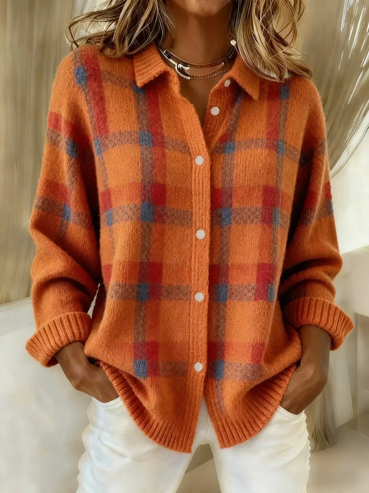 Orange plaid button-up shirt with a relaxed fit, worn by a model with hands in pockets, against an indoor backdrop.