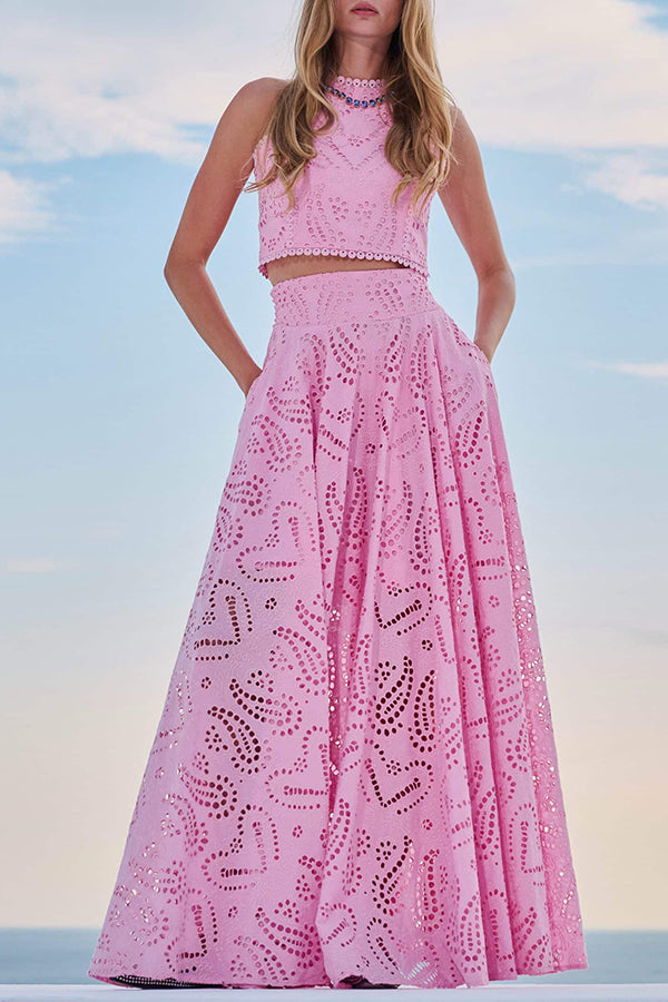 Model in a pink embroidered top and high-waist maxi skirt posing against a clear sky background.