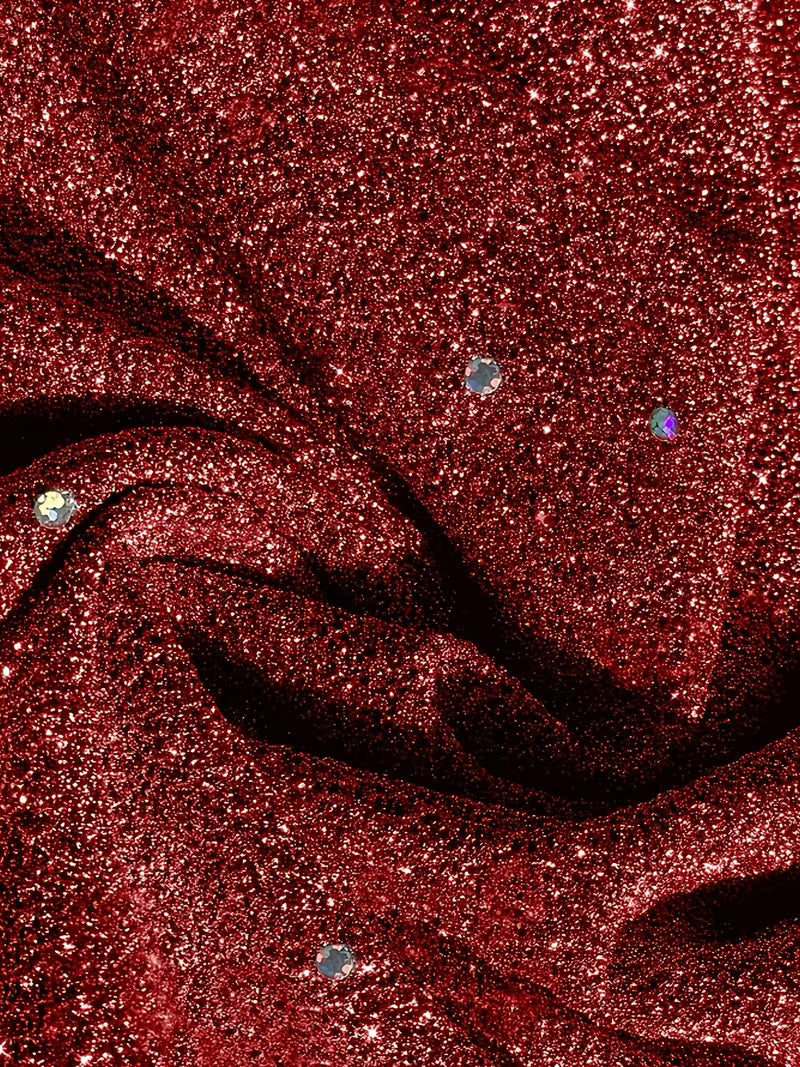 Detailed view of red dress fabric featuring sparkling dots and folds, showcasing texture and shine.