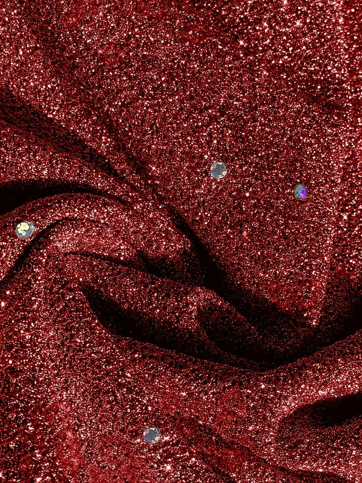 Detailed view of red dress fabric featuring sparkling dots and folds, showcasing texture and shine.