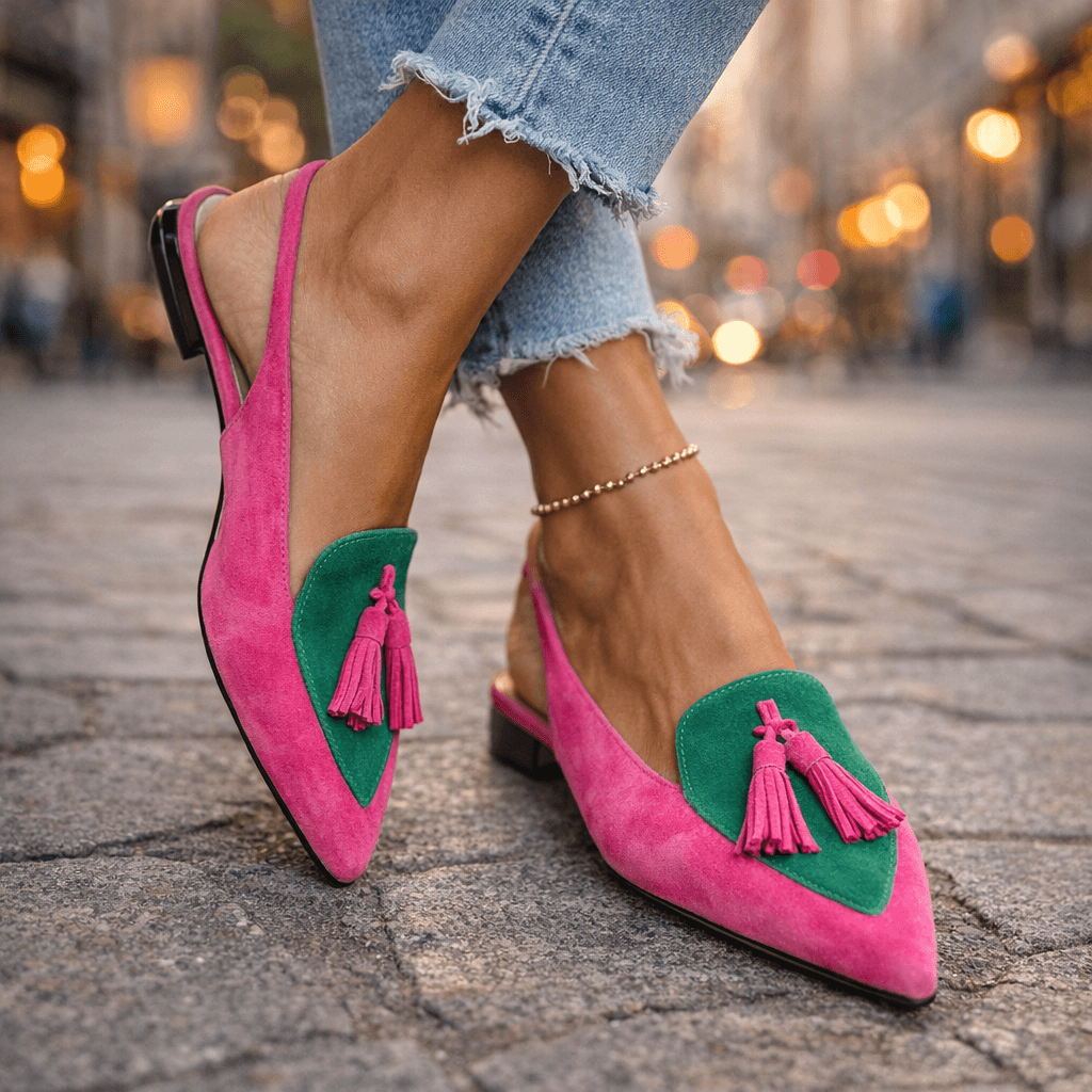 Pink and green sandals with tassels, worn with ripped jeans, on textured pavement.