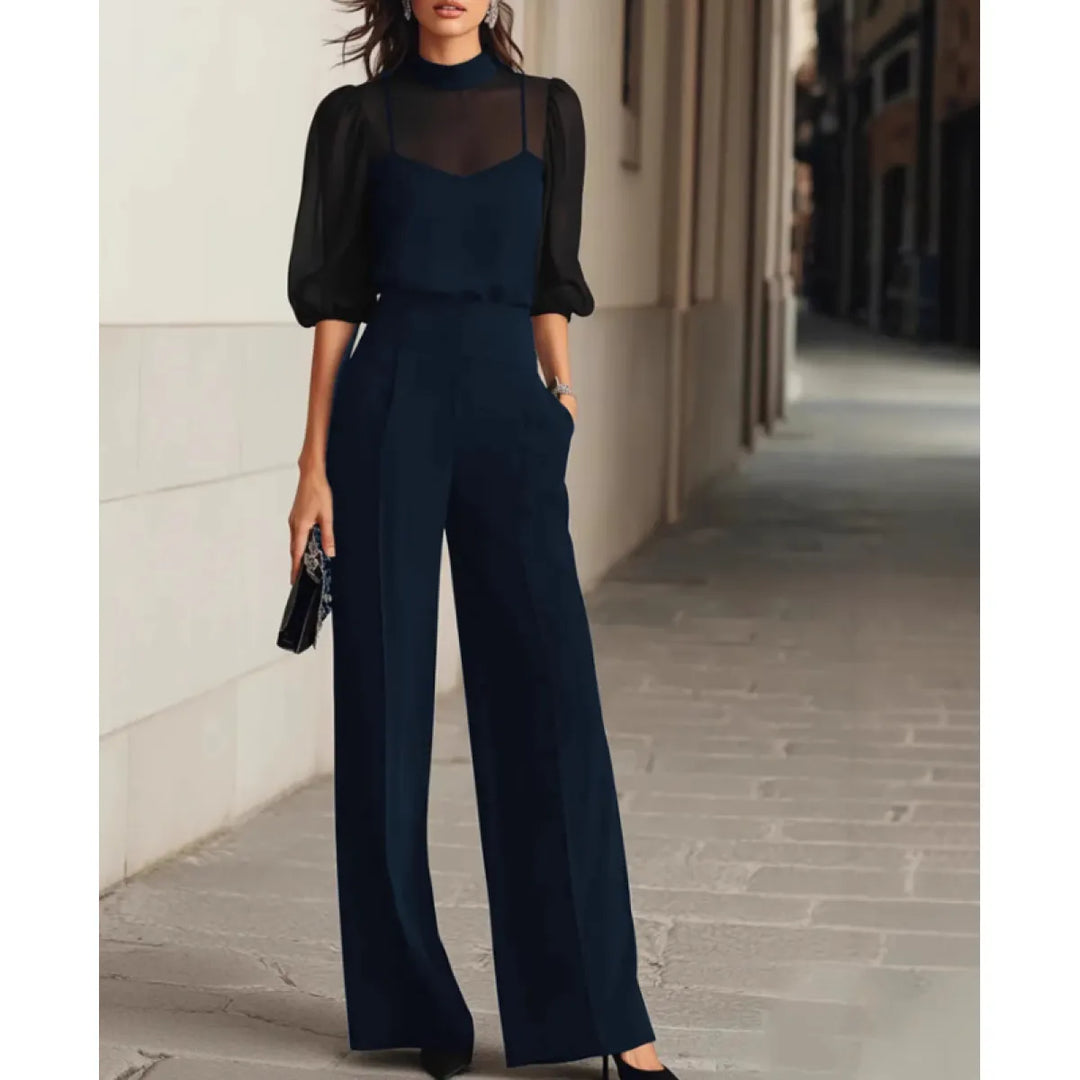 Chic navy three-piece set, featuring a sheer blouse and wide-leg pants, accessorized with a clutch in an elegant cityscape.
