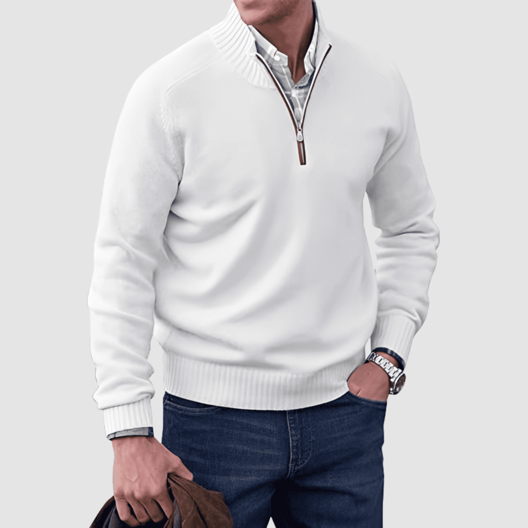 Model in white zip pullover with ribbed collar and cuffs, holding a jacket. Paired with jeans, set against a plain background.
