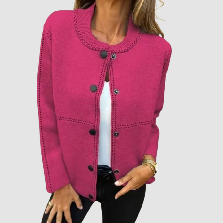 Pink jacket with round collar, button closure, worn over white top and black pants in a studio setting.