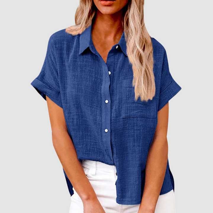 Navy blue casual blouse with short sleeves and front buttons, worn in white jeans. Studio background.