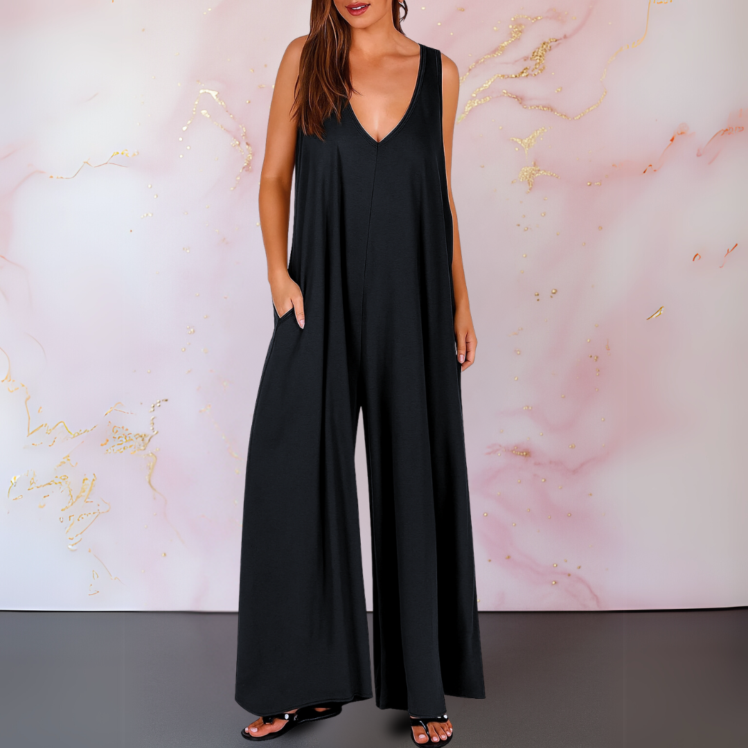 Black V-neck jumpsuit with wide legs, modeled against a pink and gold marbled backdrop.