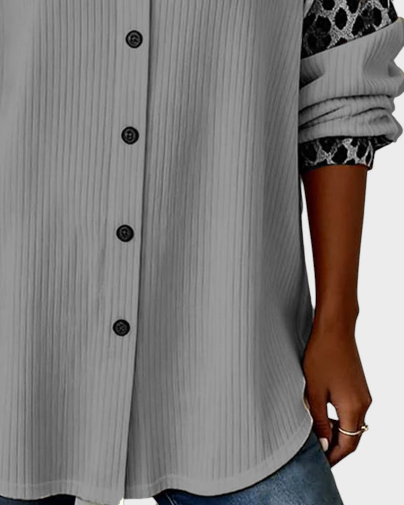 Close-up of leopard print button-down shirt bottom. Gray shirt with black buttons and patterned cuffs in a studio.
