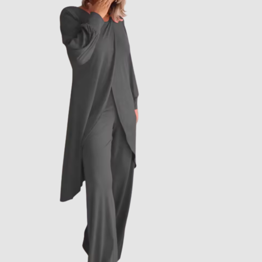 Model wearing a charcoal long-sleeve 2-piece set in a studio, hand covering face, white background.