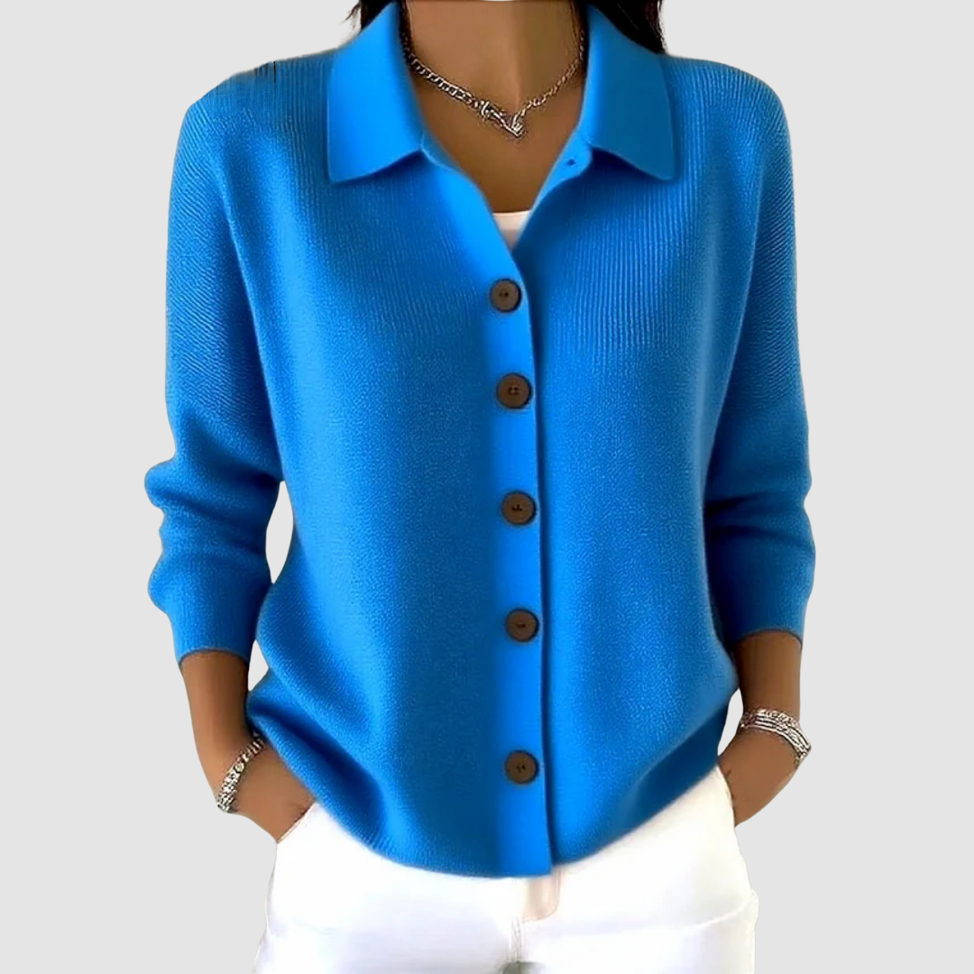Blue button-up knit cardigan with brown buttons, worn with white pants in a studio setting.