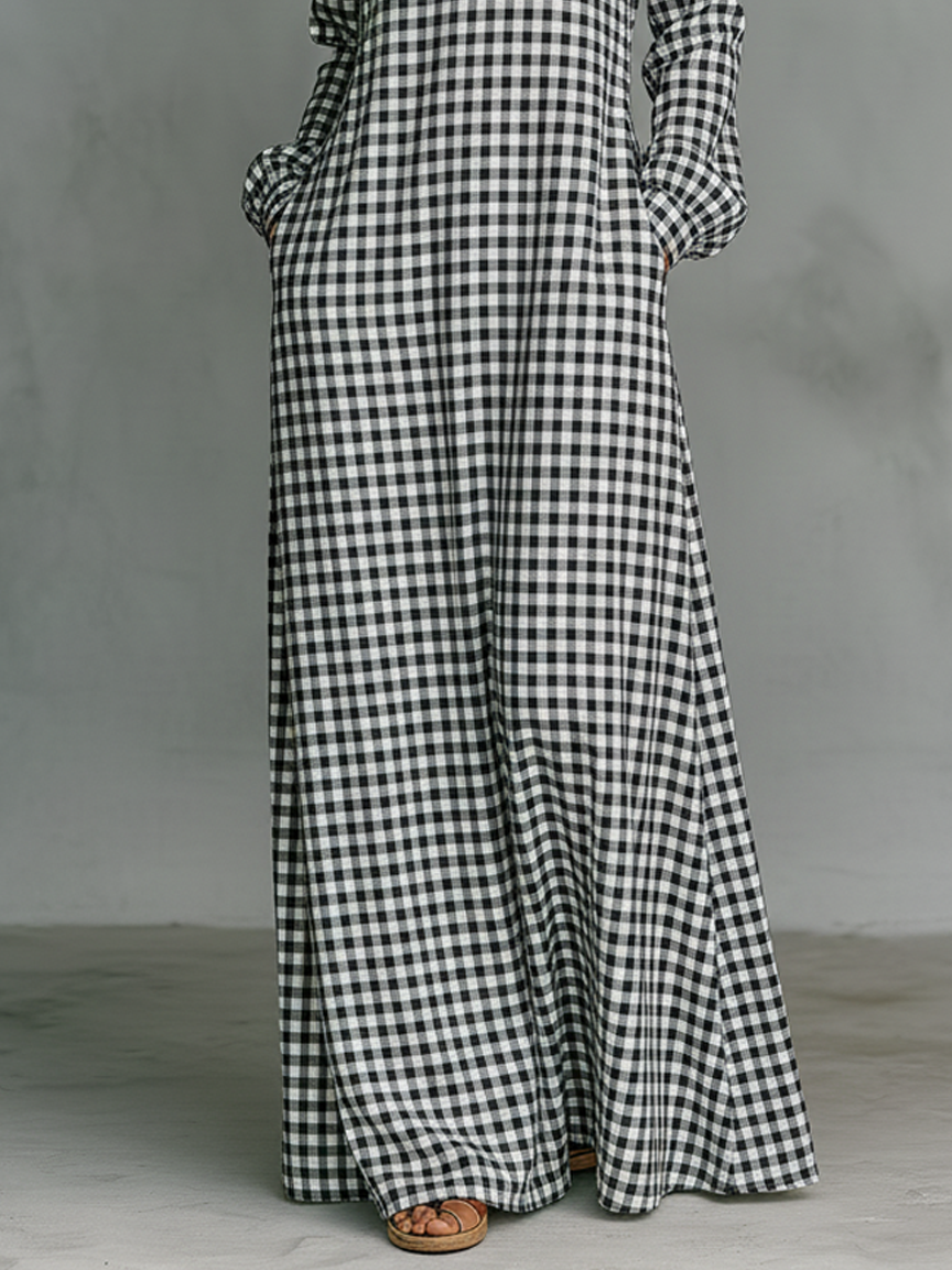 Close-up of black and white plaid maxi dress hem and sandals on model in a studio with a gray floor.