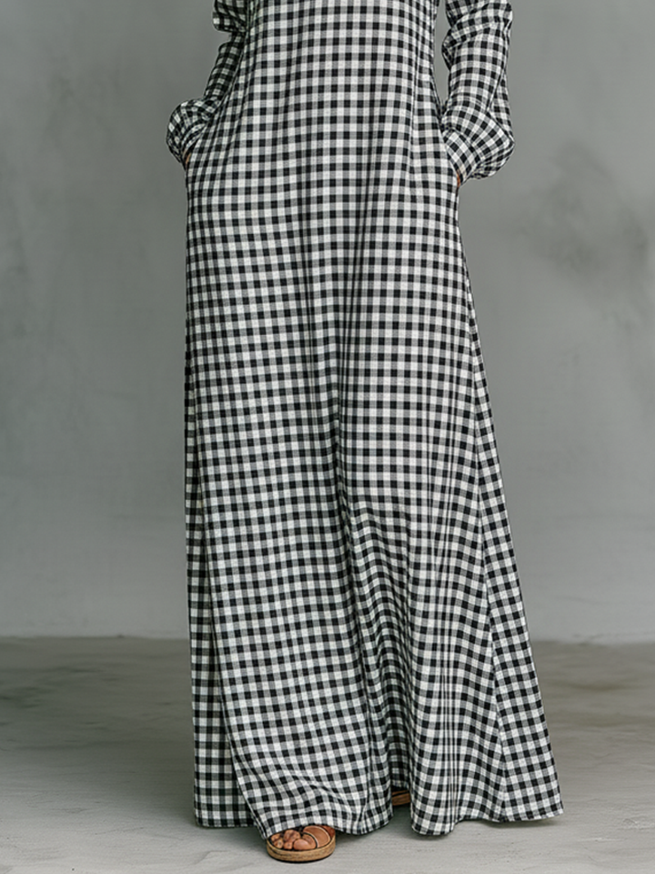 Close-up of black and white plaid maxi dress hem and sandals on model in a studio with a gray floor.